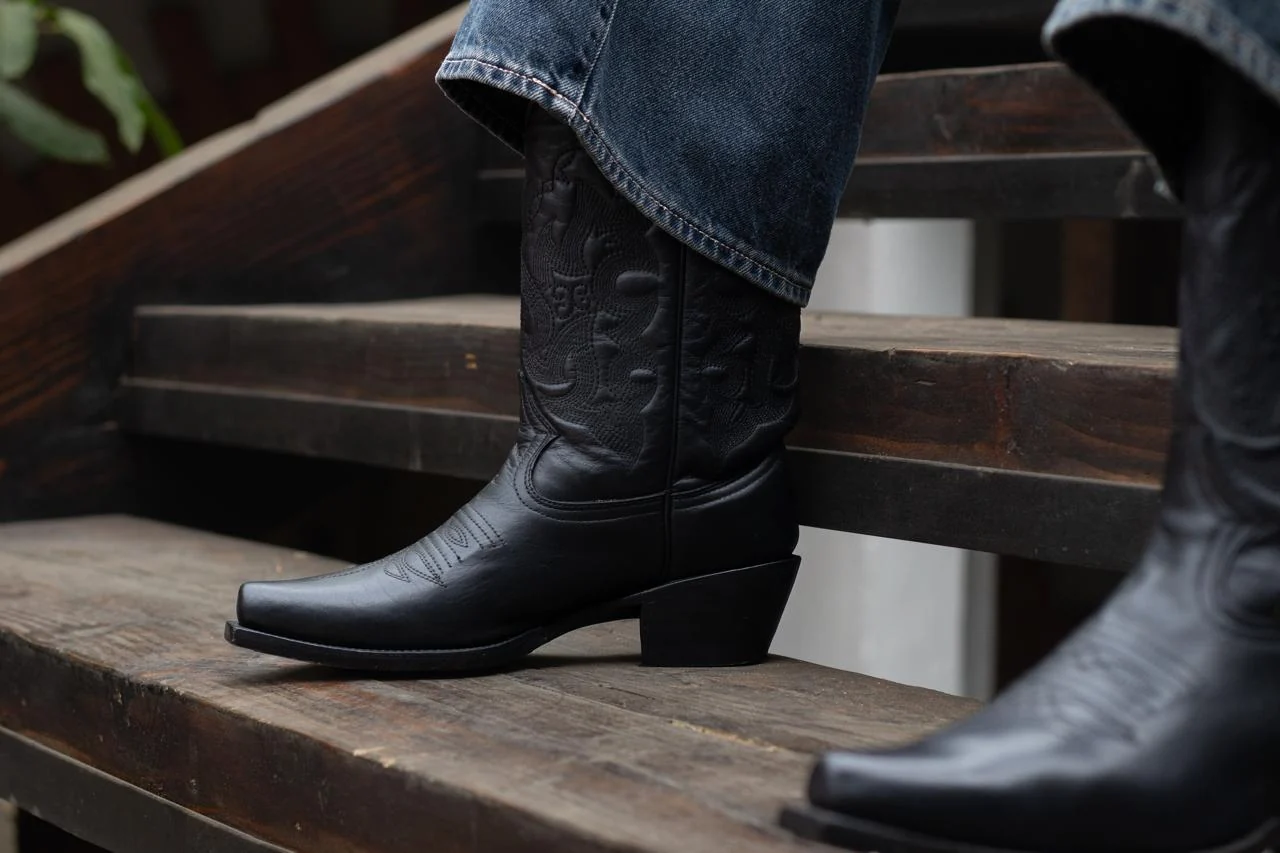 Fotografía de producto: detalle de botas negras sobre escalones de madera