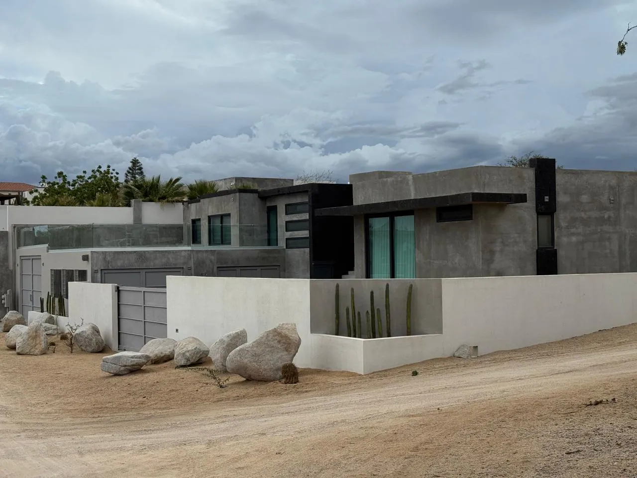 Fachada de una residencia del portafolio de PROYECTCONS, con muros de concreto, piedra y cactus