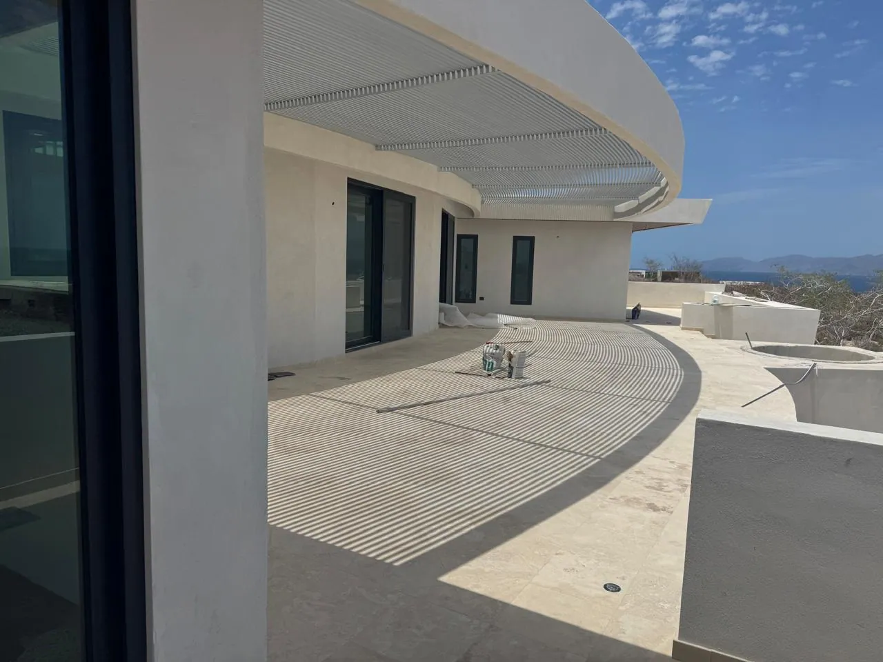 Terraza de una residencia del portafolio de PROYECTCONS, con pérgola curva y sombras sobre el piso